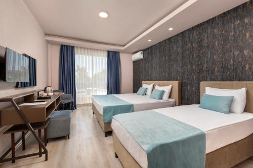 a hotel room with two beds and a desk at Hotella Resort & Spa in Belek