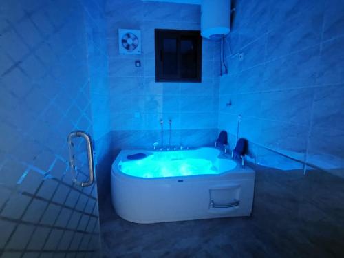 a white bath tub in a bathroom with blue lighting at شقق بيوتات الريف للشقق المخدومة in Najran