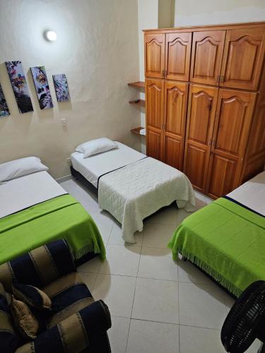 a bedroom with two beds with green sheets at GUADALUPE 102 in El Charquito