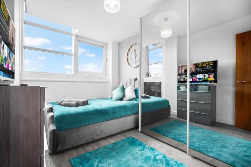 Schlafzimmer mit einem Bett mit blauer Bettwäsche und Spiegeln in der Unterkunft Luxury stay with scenic views in Brierley Hill