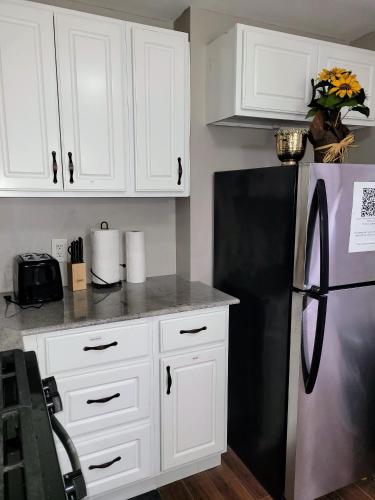 a kitchen with white cabinets and a black refrigerator at Apartment with Brand new furniture and large parking in West Seneca