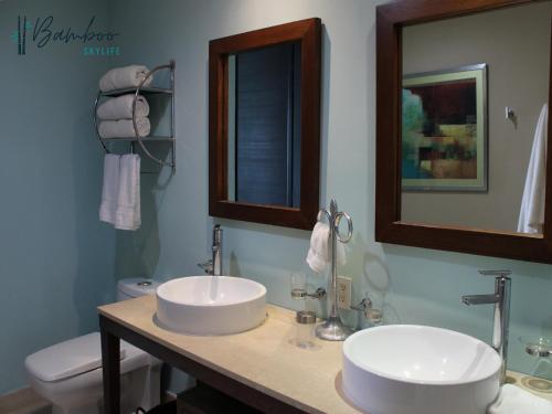 a bathroom with two sinks and a toilet and a mirror at Icon Vallarta Beach front By Bamboo Skylife in Puerto Vallarta