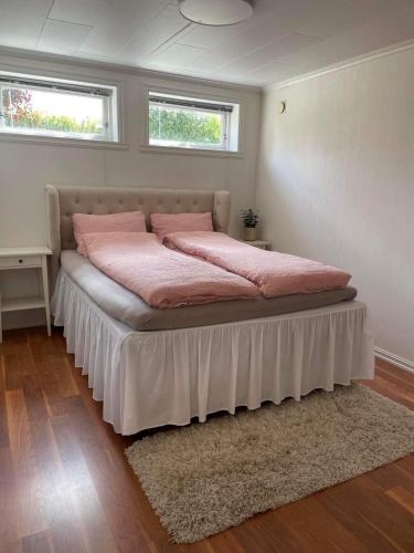 1 Schlafzimmer mit einem Bett mit rosa Bettwäsche und 2 Fenstern in der Unterkunft Leilighet til leie på Klepp nært Borestranden in Klepp