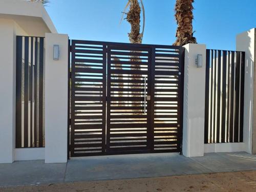 a black gate with a palm tree behind it at Casa 337 -New home with garage & community pool in Puerto Peñasco