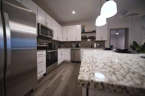 a kitchen with white cabinets and a stainless steel refrigerator at Optimum - Rock Out and Relax! in Birmingham