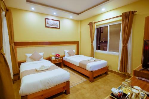 una camera d'albergo con due letti e una televisione di Paradise Boutique Hotel a Pokhara