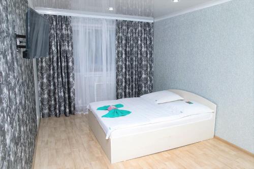 Un pequeño dormitorio con una cama blanca y una ventana en Хельсенки, en Petropavlovsk