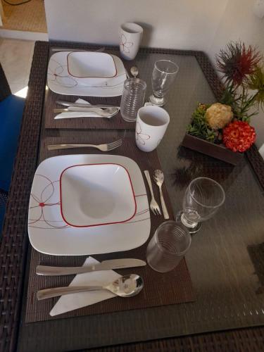 a table with white and red plates and silverware at ESTUDIO 21 in Barra de Navidad