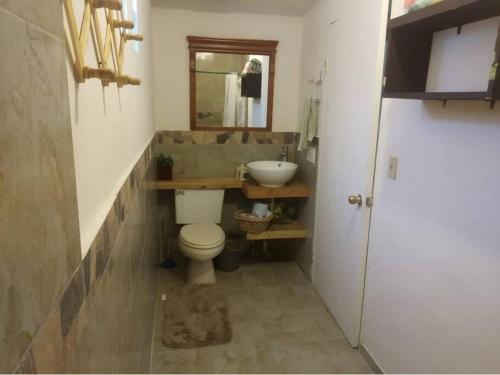 Un baño con inodoro, lavabo y espejo. en Casa Rustico 117, en Puerto Peñasco