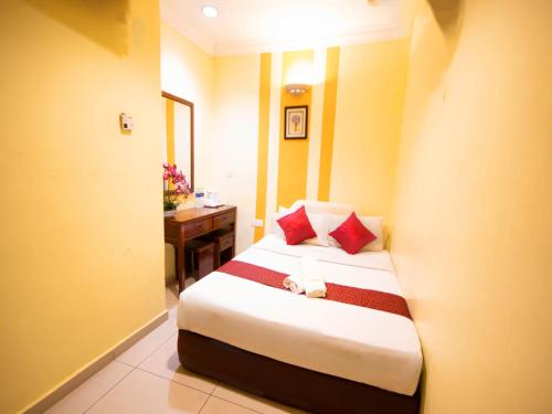 a bedroom with a bed with red pillows and a desk at Sun Inns Hotel Puchong Near IOI Puchong in Puchong
