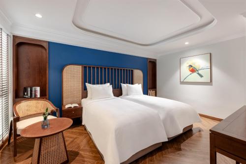 a bedroom with a large white bed and a table at La Siesta Classic Hang Thung in Hanoi