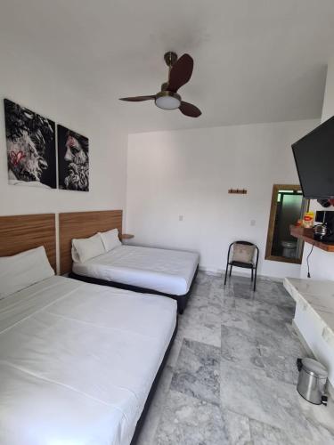 two beds in a room with a ceiling fan at Casa blanca Oaxtepec Tlayacapan in Oaxtepec