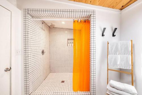 an orange shower curtain in a bathroom with white tiles at Walk to coffee, bars, eats — The Cozy Bungalow in Austin