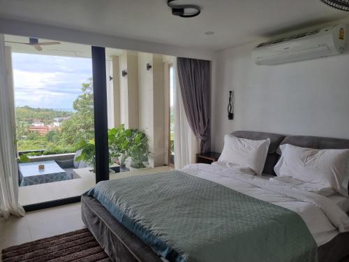 a bedroom with a large bed and a large window at Magic suites in Choeng Mon Beach