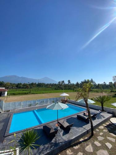 a large swimming pool with an umbrella and a resort at Pondok Tetebatu Cottages and Cafe in Tetebatu