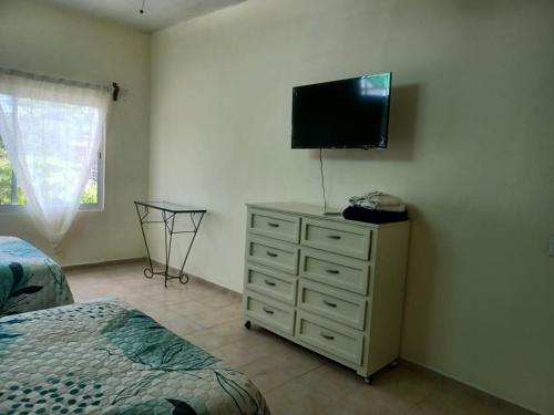 a bedroom with a bed and a dresser with a television on the wall at Casa Amelia in San Blas