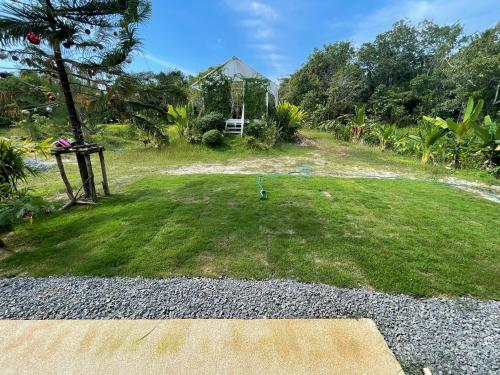 a yard with a grassy area with a house at Quiet LakeHouse Appartement on Memory Beach road in Khao Lak
