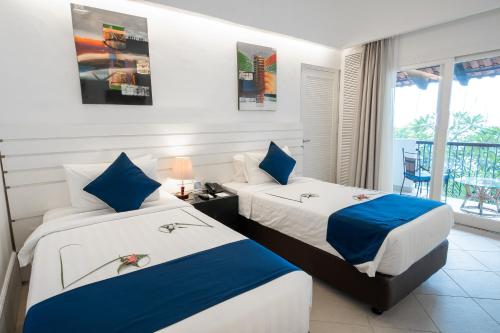 two beds in a hotel room with a balcony at Nongsa Point Marina in Nongsa