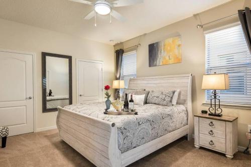 ein Schlafzimmer mit einem großen weißen Bett mit einer Kommode und einem Spiegel in der Unterkunft DreamCatcher House - Elite 7 Bed Luxury Escape in Kissimmee