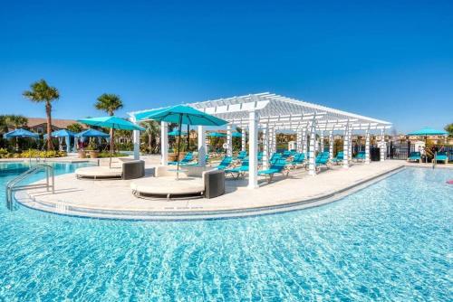 einen Pool mit Stühlen und Sonnenschirmen in einem Resort in der Unterkunft DreamCatcher House - Elite 7 Bed Luxury Escape in Kissimmee