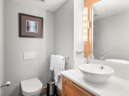 a white bathroom with a sink and a toilet at Ski In/Out, Steam Shower, Pool, Hot Tub, Sauna in Whistler