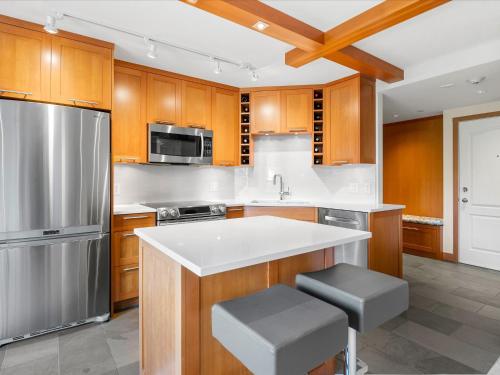 a kitchen with wooden cabinets and a stainless steel refrigerator at Ski In/Out, Steam Shower, Pool, Hot Tub, Sauna in Whistler