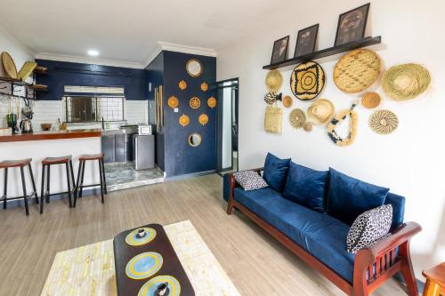 a living room with a blue couch and a kitchen at Oasis Villa Home Kampala in Kampala