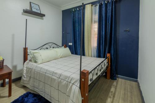 sypialnia z łóżkiem, niebieskimi ścianami i oknem w obiekcie Oasis Villa Home Kampala w mieście Kampala