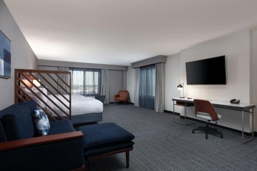 um quarto de hotel com uma cama, uma secretária e uma televisão em Courtyard by Marriott Wichita at Old Town em Wichita