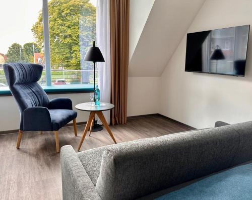 a living room with a couch and a chair and a table at Hotel Schöne Aussicht in Wilhelmshaven