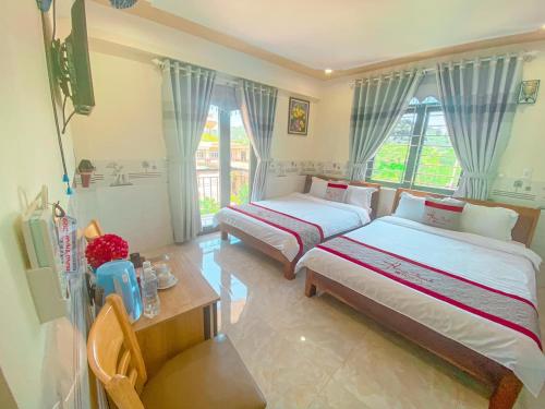 a bedroom with two beds and a table and window at KHÁCH SẠN HƯNG THỊNH - Lý Sơn in Ly Son