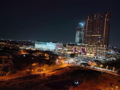 una città illuminata di notte con edifici e luci di Apartemen Pakuwon Educity yale a Surabaya