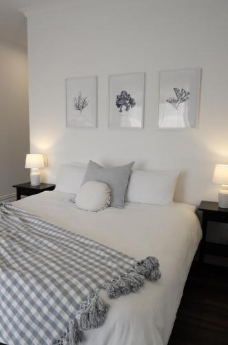 1 dormitorio con 1 cama con 2 lámparas y cuadros en la pared en Yallingup Homestead Guest House en Dunsborough