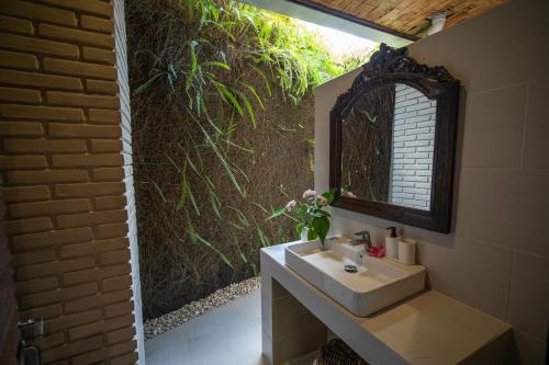 ein Bad mit einem Waschbecken und einem Spiegel in der Unterkunft Puri Bayu in Ubud