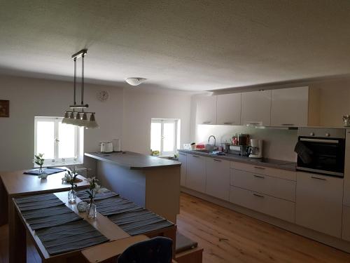 uma cozinha com armários brancos e uma mesa em Riederhof em Flintsbach am Inn