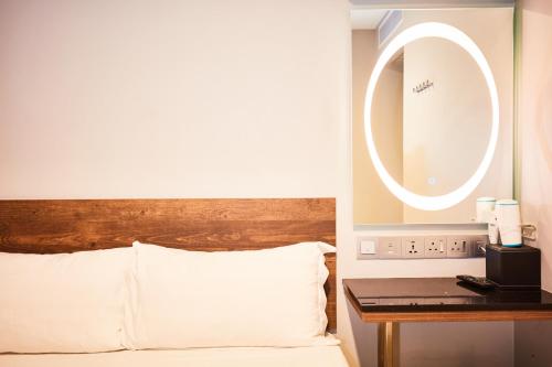 a bed with a wooden headboard and a round mirror at ibis budget Singapore Selegie in Singapore