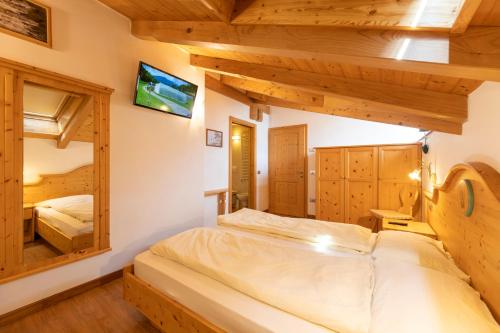 een slaapkamer met 2 bedden in een kamer met houten plafonds bij B.& B. Corradini in Castello di Fiemme