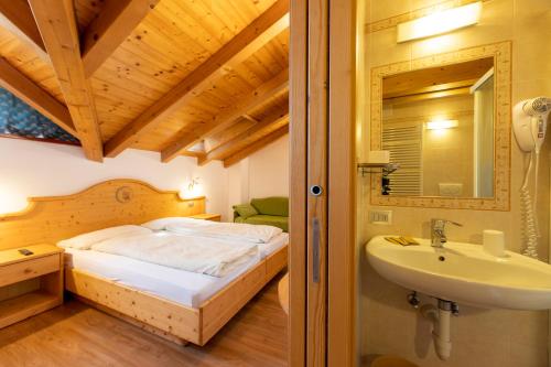 Habitación con baño con cama y lavabo. en B.& B. Corradini en Castello di Fiemme