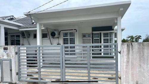 a white fence in front of a white house at Homestay Taman Tiara Paka in Paka