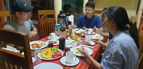 a group of people sitting around a table eating food at Kisanga Homestay in Moshi
