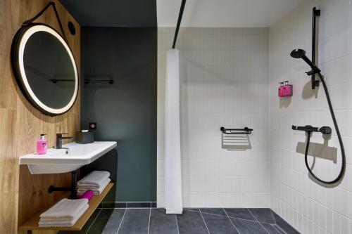 a bathroom with a sink and a shower with a mirror at Moxy Karlsruhe in Karlsruhe