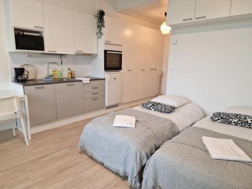 une chambre avec deux lits et une cuisine avec des placards blancs dans l'établissement Cozy apartment with a yard in Kivistö near Airport, à Vantaa