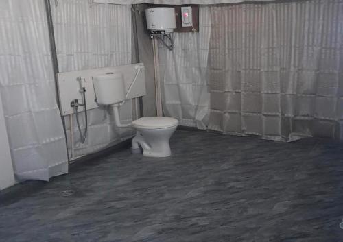 een badkamer met een wit toilet in een stal bij Trident Jungle Stay in Dandeli