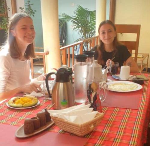 two women sitting at a table with food at Kisanga Homestay in Moshi