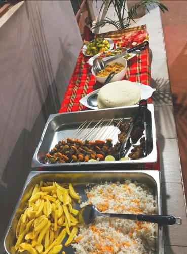 a table with several trays of food on it at Kisanga Homestay in Moshi