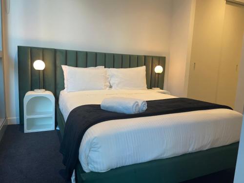 Schlafzimmer mit einem großen Bett mit einem grünen Kopfteil in der Unterkunft Superior 3 Bedroom 2 Bathroom Apt Melbourne CBD in Melbourne