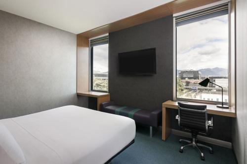 a hotel room with a bed and a desk and window at Aloft Bogotá Airport in Bogotá