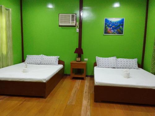 two beds in a room with a green wall at LaVeranda Beach Resort in Dauis