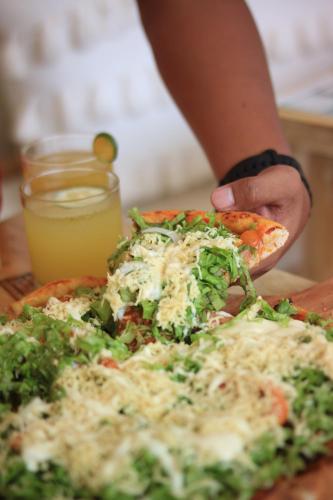 a person is taking a slice of pizza at Vela Terraces Hotel in Coron