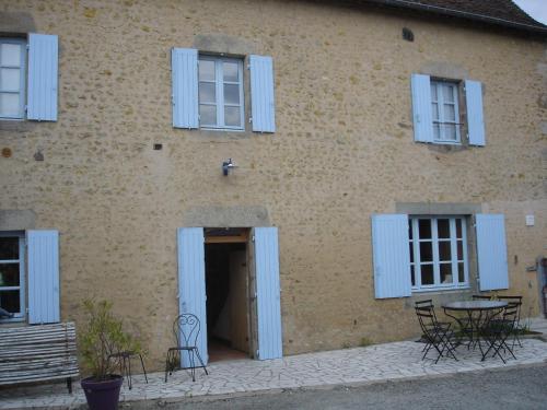 un bâtiment avec des fenêtres à volets bleus et une porte dans l'établissement Chambres d'Hôtes La Bosquetière, à Maresché